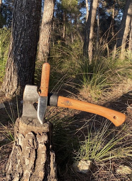 Handmade knives and axe in a forest setting