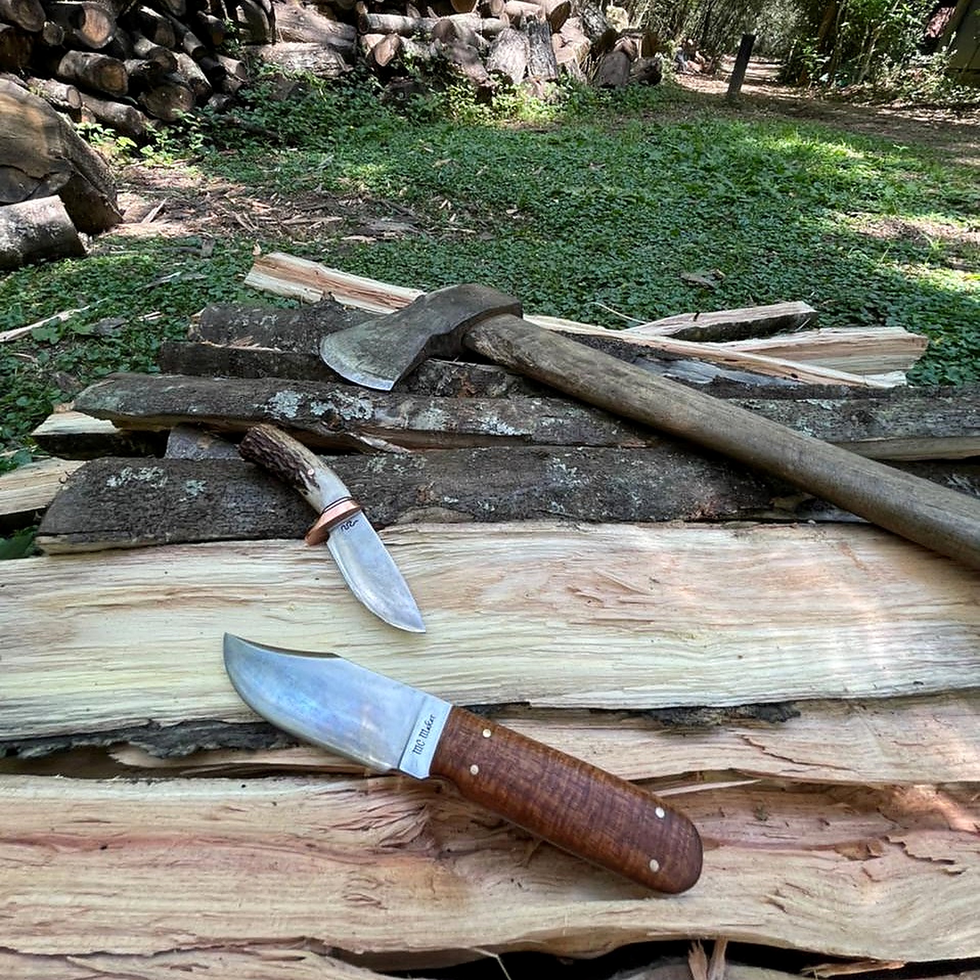 Handmade knives and tools around split wood outdoors